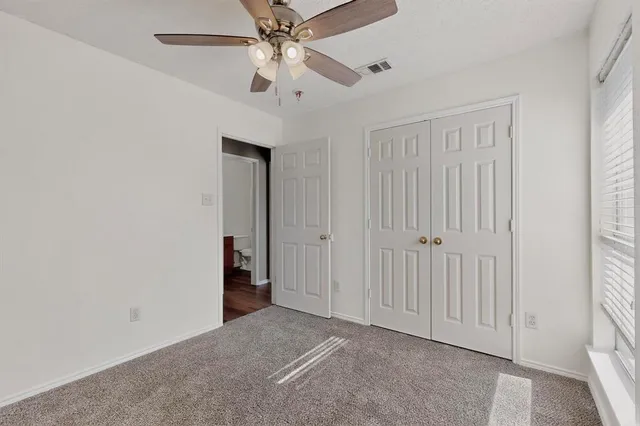 an empty room with closet and a ceiling fan