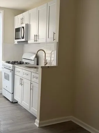 a kitchen with granite countertop white cabinets and stainless steel appliances