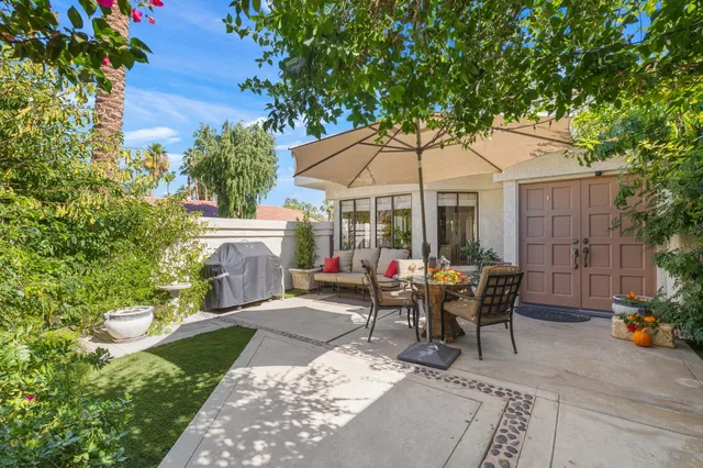 a view of a patio with a table and chairs under an umbrella