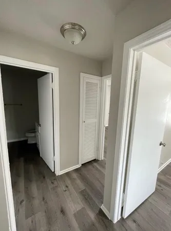 a view of a hallway with wooden floor and closet area