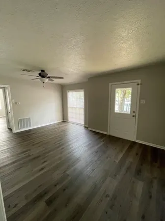 an empty room with wooden floor and windows