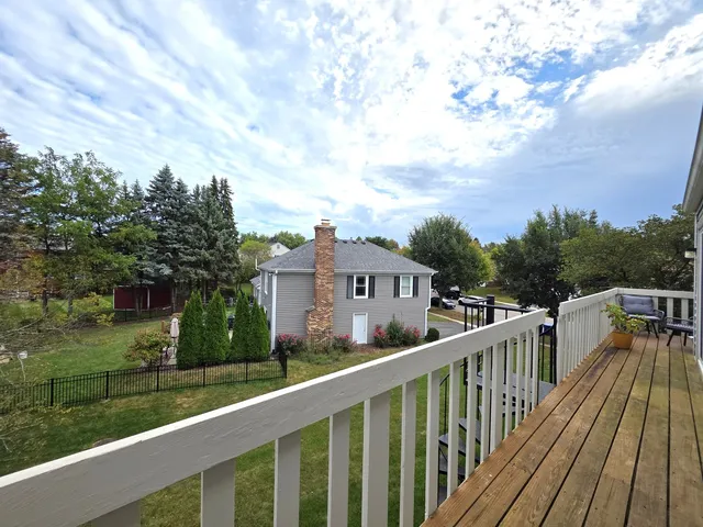a view of a house with wooden deck and trees in the background