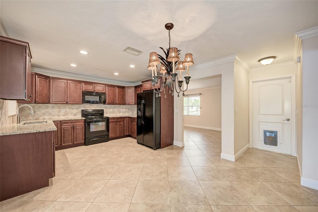 1330 Georgetowne Circle Sarasota, FL 34232 - Photo 9 of 46 a kitchen with stainless steel appliances granite countertop a refrigerator a sink dishwasher a stove and white cabinets with wooden floor