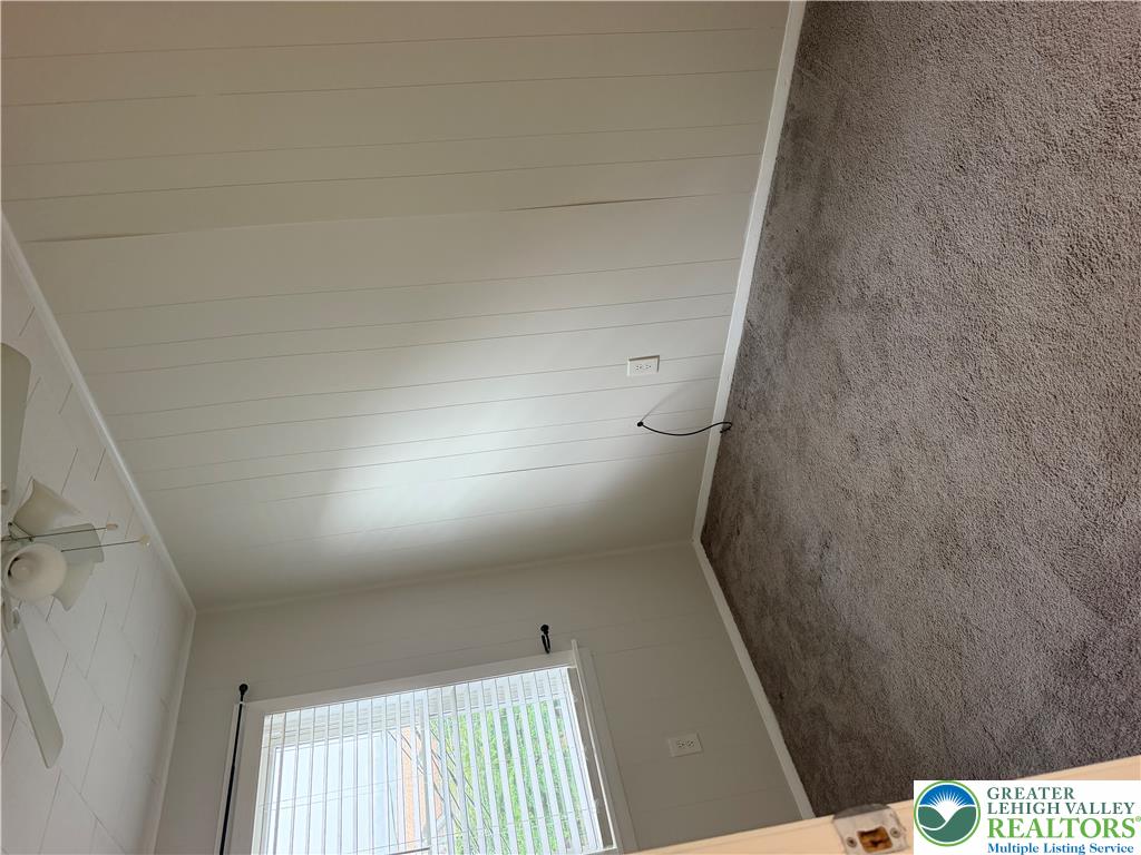 649 Furnace Street Emmaus, PA 18049 - Photo 8 of 10 Plank-style paneling lines the ceiling and walls of this cozy bedroom featuring soft carpeting.
