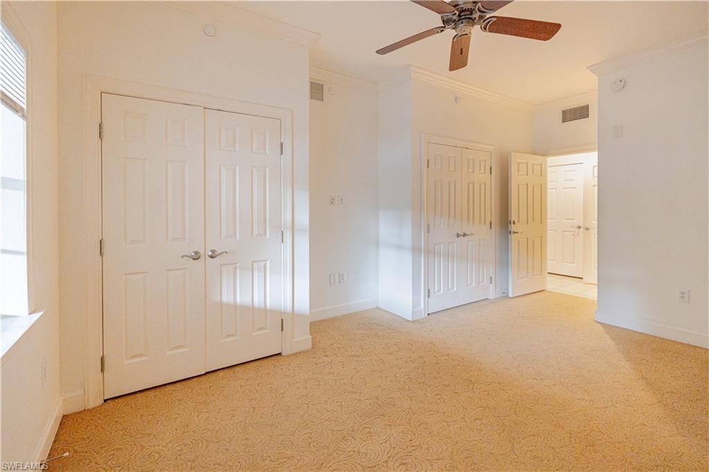 1362 Centre Ct Ridge Drive, Unit 101 Reunion, FL 34747 - Photo 20 of 25 Unfurnished bedroom with multiple closets, ornamental molding, ceiling fan, and light colored carpet