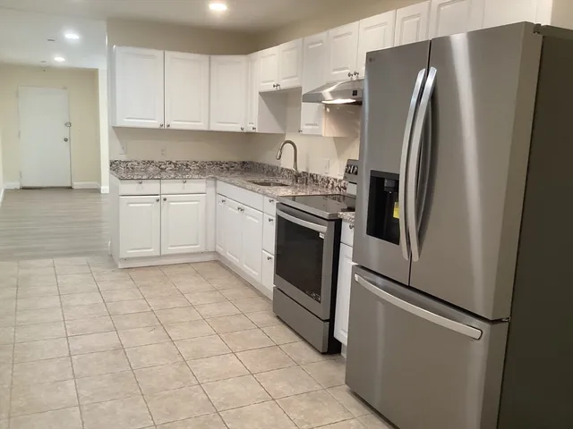 a kitchen with stainless steel appliances granite countertop a refrigerator and a sink