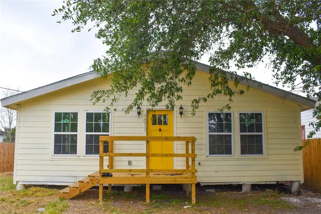 a backyard of a house with wooden fence and a large tree