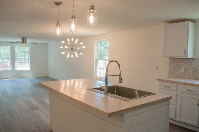 a kitchen with kitchen island granite countertop a sink a counter space and cabinets