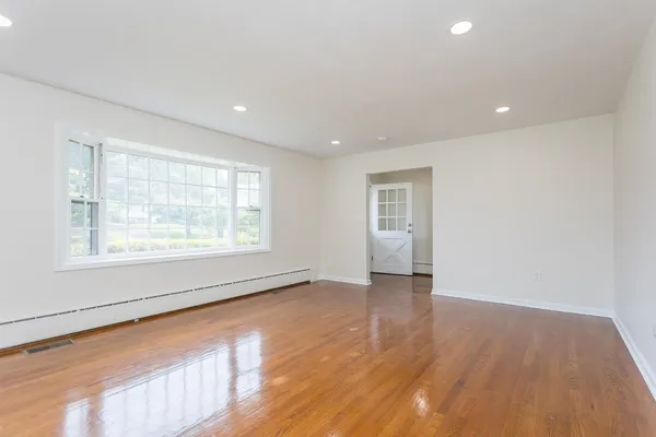 a view of an empty room with wooden floor and a window