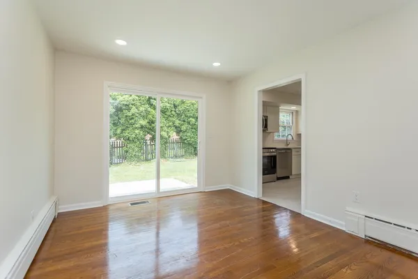 a view of an empty room with wooden floor and a window