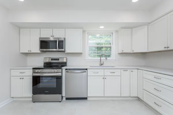 a kitchen with white cabinets stainless steel appliances and window