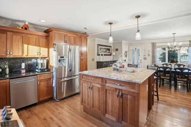a kitchen with stainless steel appliances granite countertop a refrigerator a stove and a wooden floors