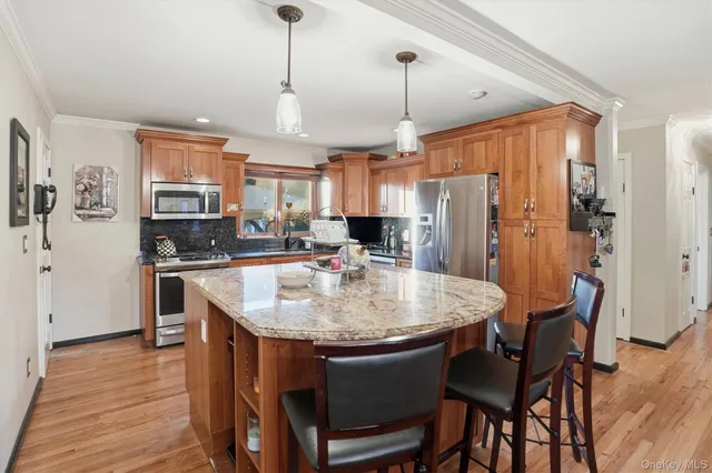 a kitchen with stainless steel appliances granite countertop a stove a refrigerator a oven a sink a dining table and chairs with wooden floor