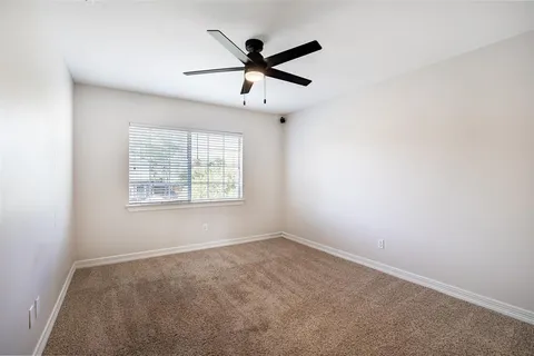 an empty room with ceiling fan and windows