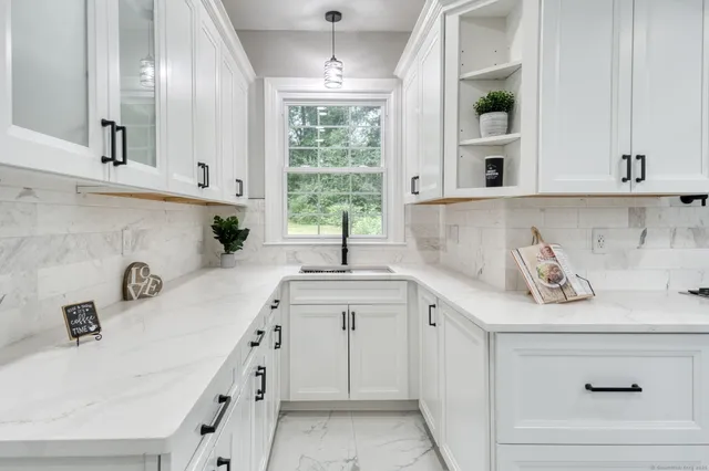 a kitchen with white cabinets and window