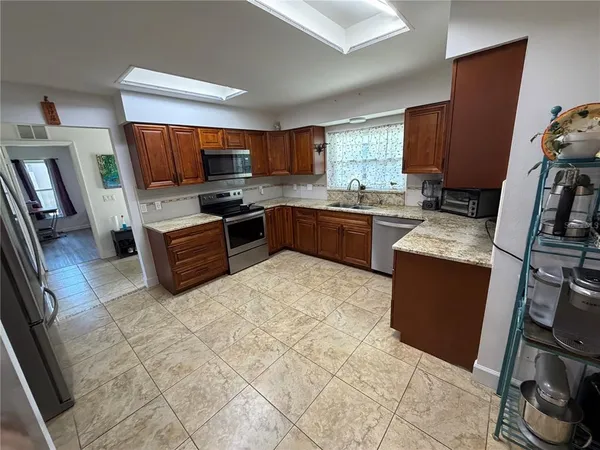 a kitchen with stainless steel appliances granite countertop a stove top oven a sink a dining table and chairs
