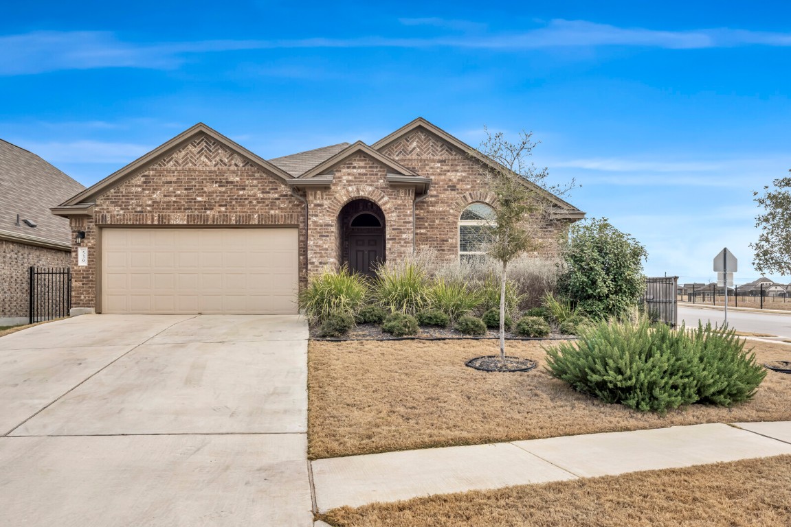 View of front of home with concrete driveway, brick siding, and an attached garage