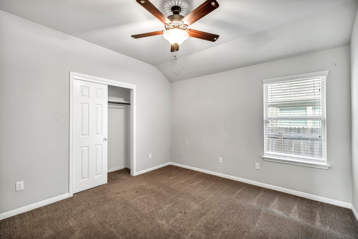 539 Merlin Lane Leander, TX 78641 - Photo 11 of 18 Unfurnished bedroom featuring vaulted ceiling, dark colored carpet, a closet, and ceiling fan