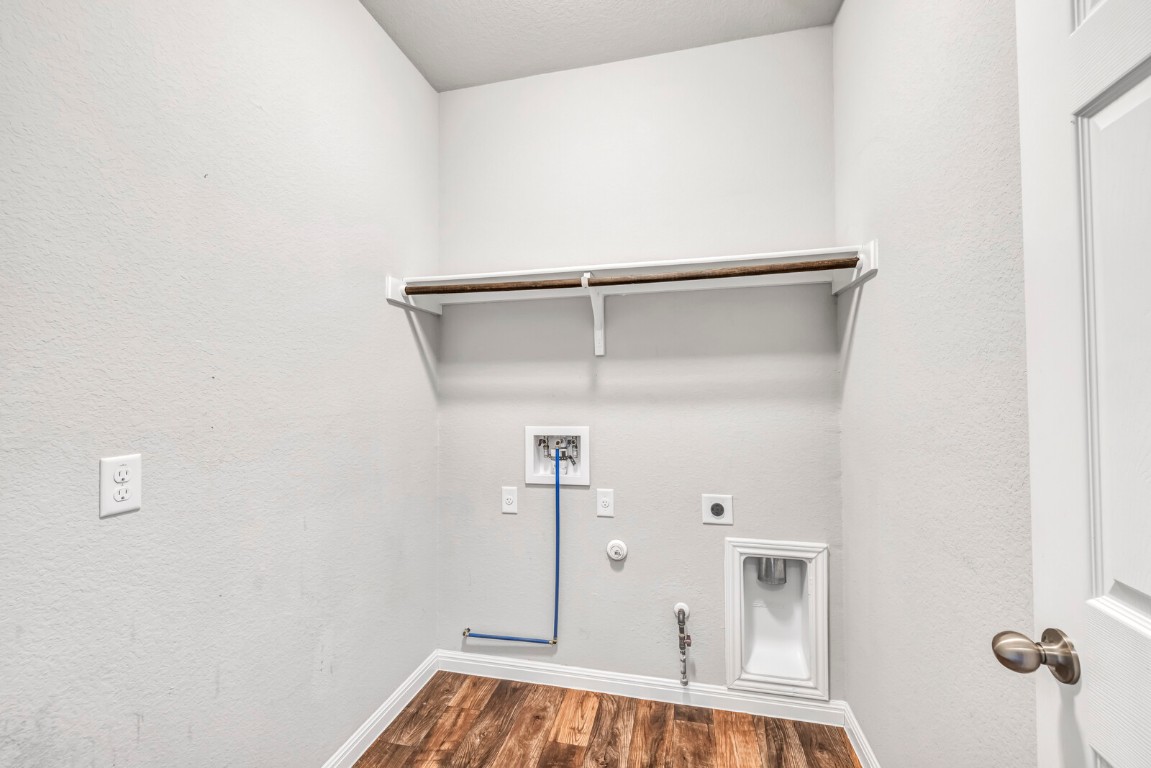 539 Merlin Lane Leander, TX 78641 - Photo 15 of 18 Washroom featuring hookup for a gas dryer, a textured wall, dark wood-style floors, washer hookup, and hookup for an electric dryer