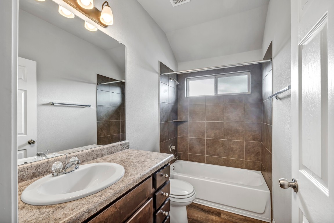 539 Merlin Lane Leander, TX 78641 - Photo 4 of 18 Full bath featuring shower / tub combination, vanity, vaulted ceiling, and dark wood-style floors