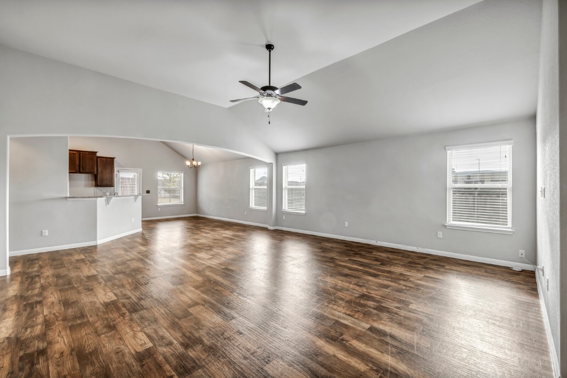 539 Merlin Lane Leander, TX 78641 - Photo 5 of 18 Unfurnished living room featuring a chandelier, dark wood-type flooring, a ceiling fan, and vaulted ceiling