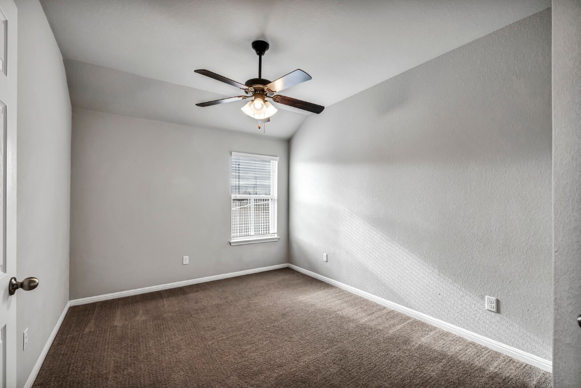 539 Merlin Lane Leander, TX 78641 - Photo 6 of 18 Spare room featuring vaulted ceiling, a ceiling fan, and dark colored carpet