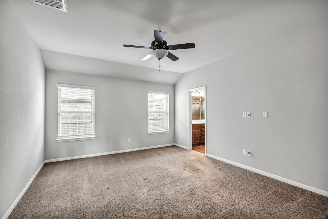 539 Merlin Lane Leander, TX 78641 - Photo 9 of 18 Unfurnished bedroom with ensuite bathroom, carpet floors, ceiling fan, and vaulted ceiling