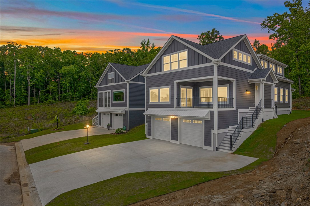 1230 Melton Road, Unit 216 West Union, SC 29696 - Photo 1 of 49 A striking gray residence with white trim and multiple balconies, nestled against a backdrop of lush trees under a vibrant sunset.