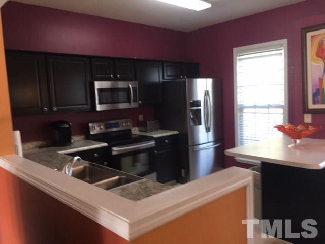7010 Mead Lane Raleigh, NC 27613 - Photo 11 of 22 a kitchen with stainless steel appliances wooden cabinets a sink and a stove