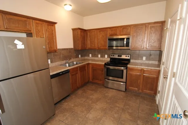 a kitchen with stainless steel appliances a refrigerator a stove a sink a microwave and cabinets