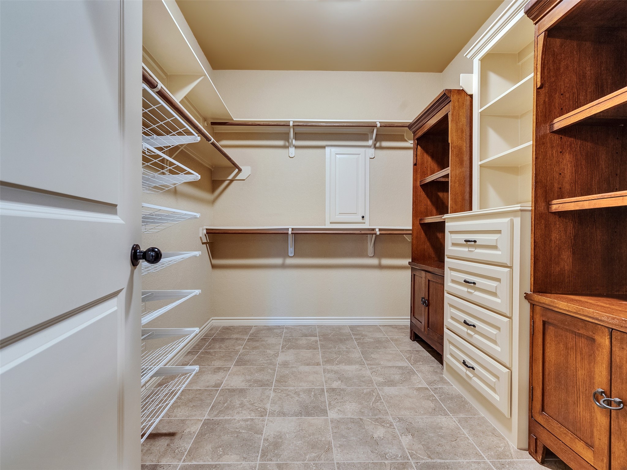 18005 Cindy Lane Conroe, TX 77302 - Photo 33 of 49 Spacious walk-in closet with ample shelving, wire racks, and wooden cabinetry for organized storage. Neutral tones and tiled flooring add a clean, sophisticated touch.