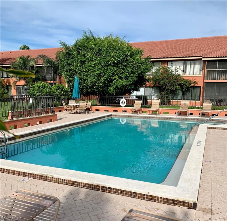 124 Cypress Way East, Unit E3 Naples, FL 34110 - Photo 4 of 4 a view of a swimming pool with a patio and a yard