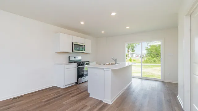 a large kitchen with a sink and wooden floor