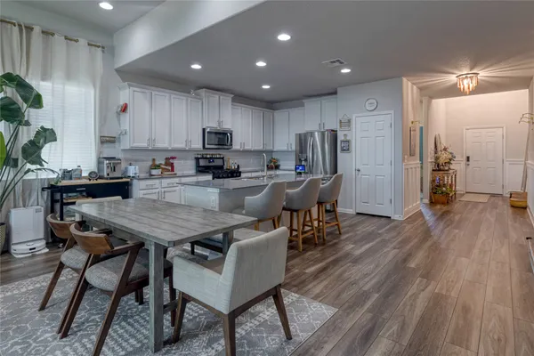 a kitchen with a table chairs refrigerator and microwave
