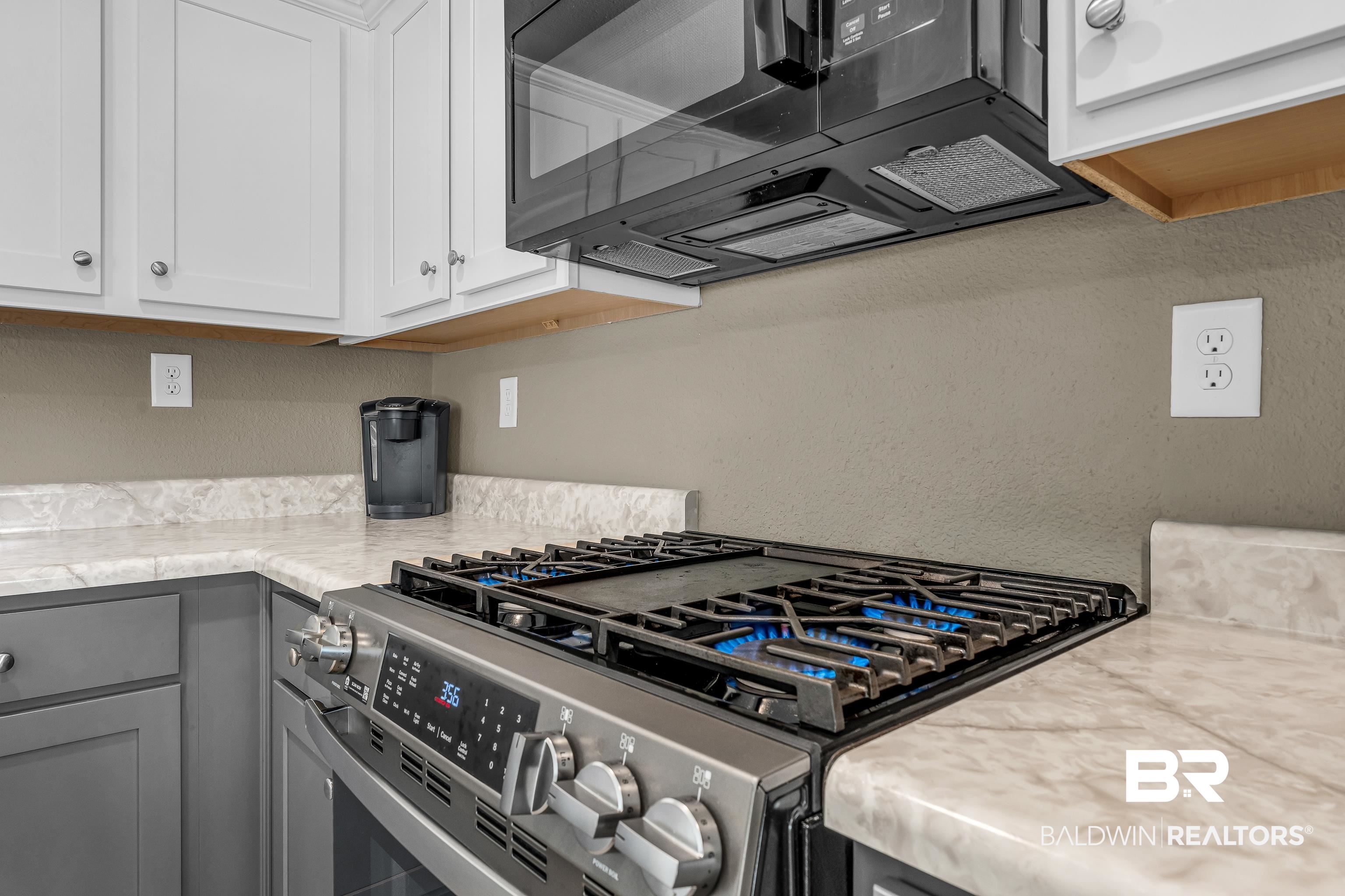 9206 Greenleaf Drive Daphne, AL 36527 - Photo 10 of 32 Kitchen with black microwave, stainless steel range with gas stovetop, white cabinets, a textured wall, and gray cabinets