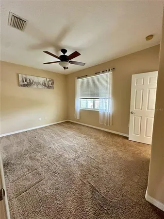 an empty room with windows and ceiling fan