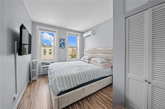 a bedroom with a bed and a flat tv screen on dresser