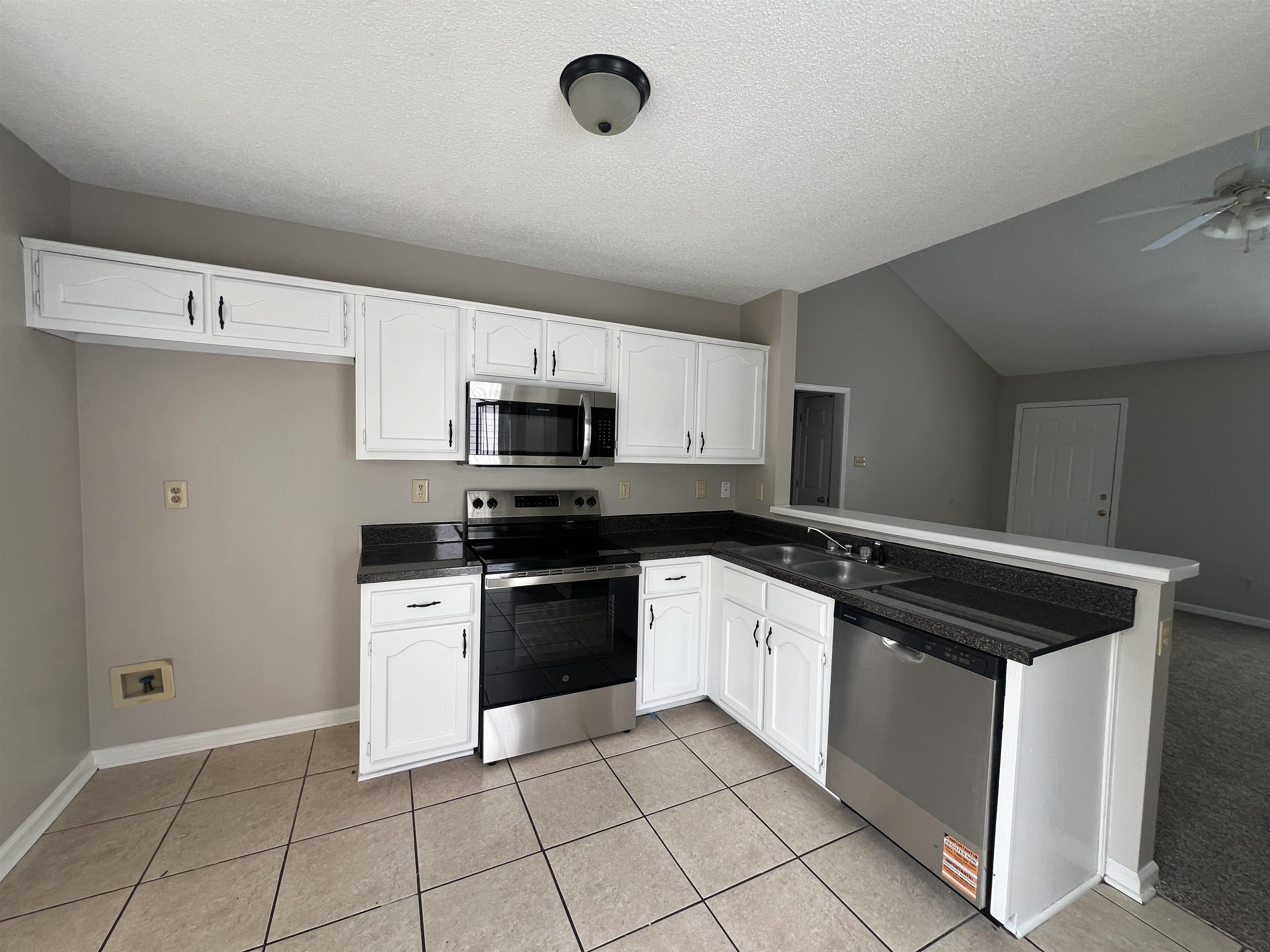 5950 Chadwell Road Millington, TN 38053 - Photo 6 of 14 Kitchen with stainless steel appliances, white cabinetry, dark countertops, and a peninsula