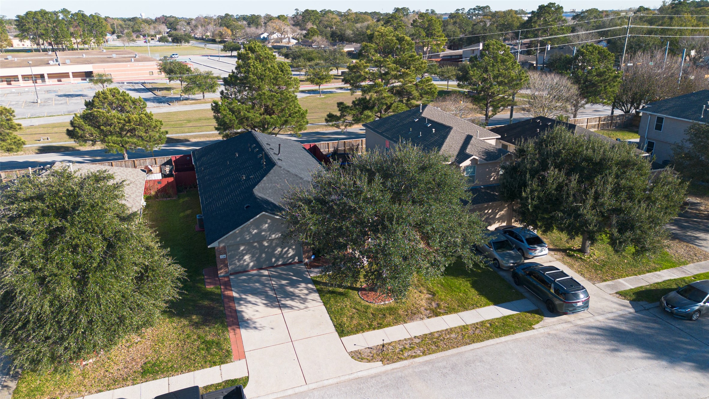 20218 Appaloosa Ridge Drive Humble, TX 77338 - Photo 40 of 44 This aerial photo showcases a cozy suburban home with a well-maintained front yard, a driveway with ample parking space, and mature trees providing shade. The neighborhood is peaceful and green, with nearby open spaces and a school visible in the background.
