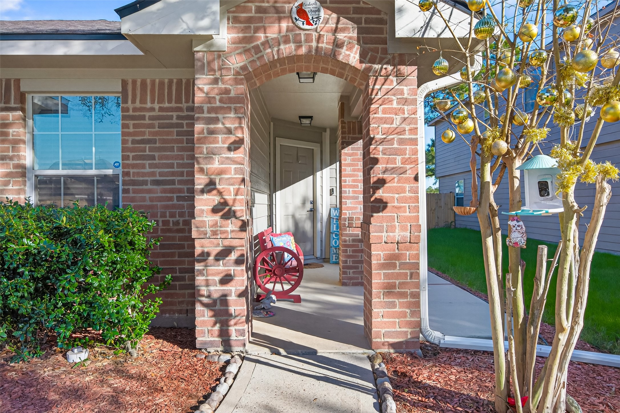 20218 Appaloosa Ridge Drive Humble, TX 77338 - Photo 7 of 44 Charming front porch with a brick archway and cozy seating area. Well-maintained landscaping includes a festive tree and a welcoming atmosphere. Ideal for relaxing and enjoying the neighborhood.
