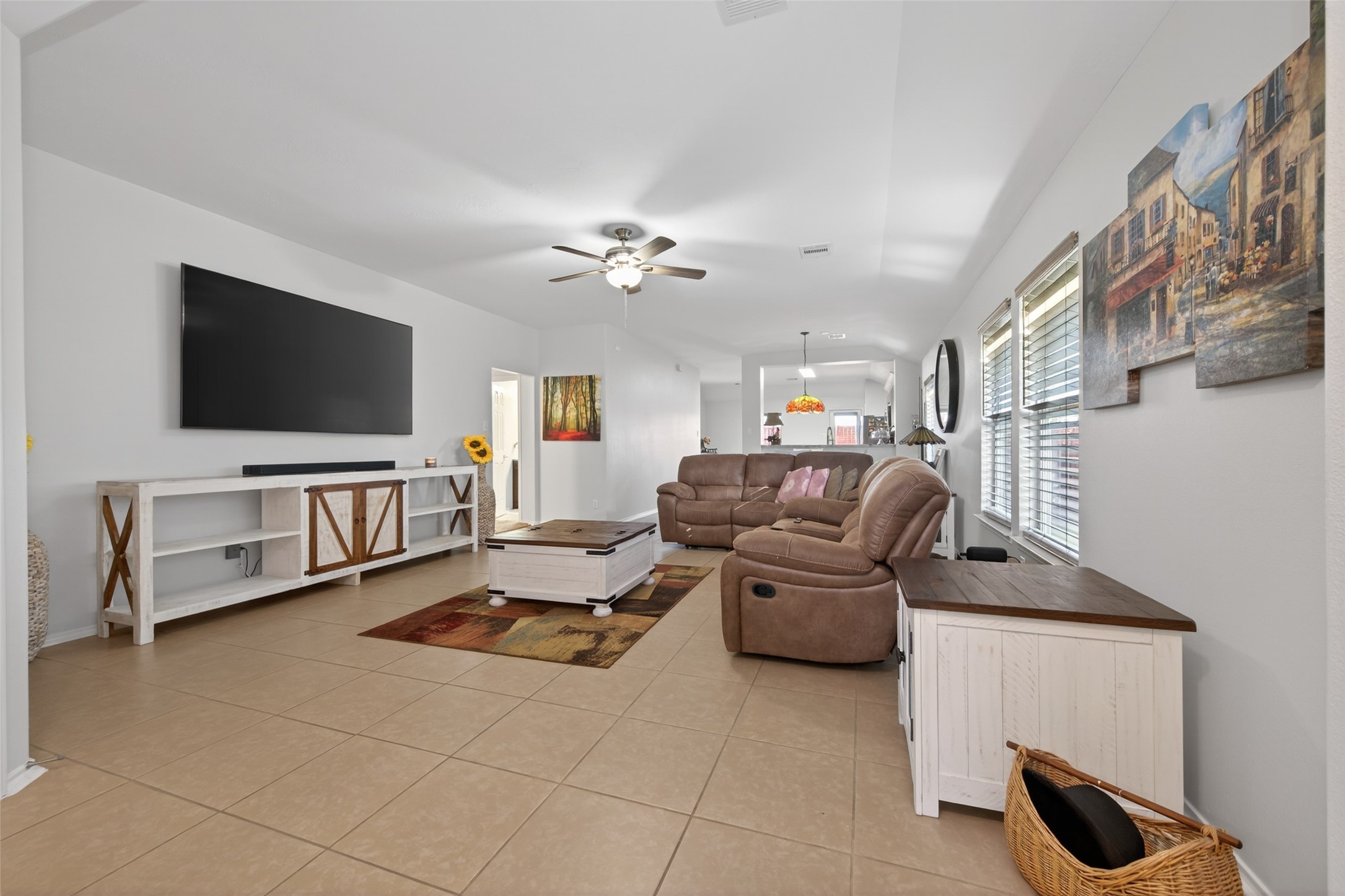 20218 Appaloosa Ridge Drive Humble, TX 77338 - Photo 9 of 44 Spacious living room with neutral tile flooring, modern ceiling fan, and ample natural light. Features comfortable seating, wall-mounted TV, and stylish furniture, perfect for relaxation and entertainment.