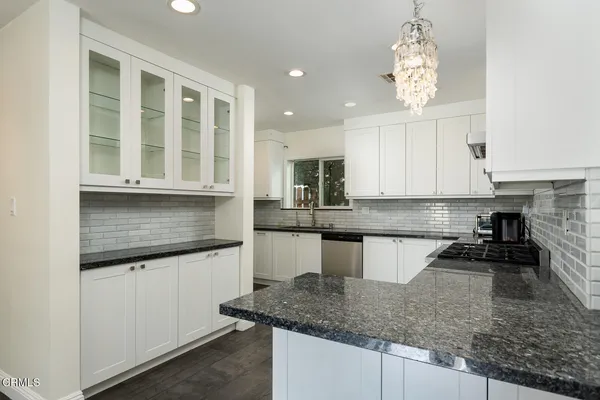 a kitchen with granite countertop white cabinets and appliances
