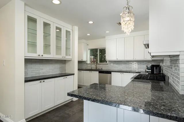 a kitchen with granite countertop white cabinets and appliances