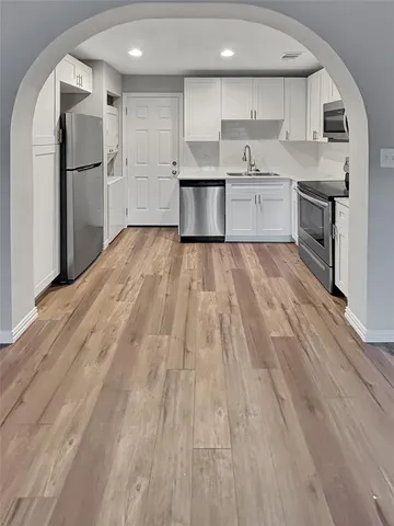 a large kitchen with stainless steel appliances granite countertop a lot of cabinets and wooden floor