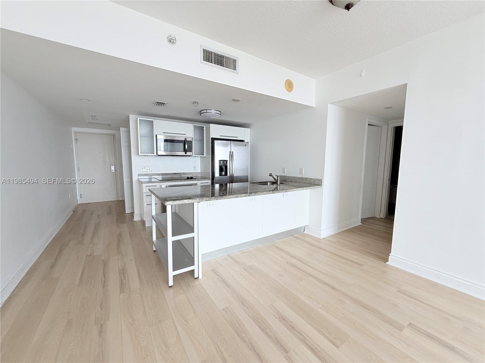 185 Southwest 7th Street, Unit 3304 Miami, FL 33130 - Photo 1 of 17 a view of a kitchen with wooden floor and electronic appliances