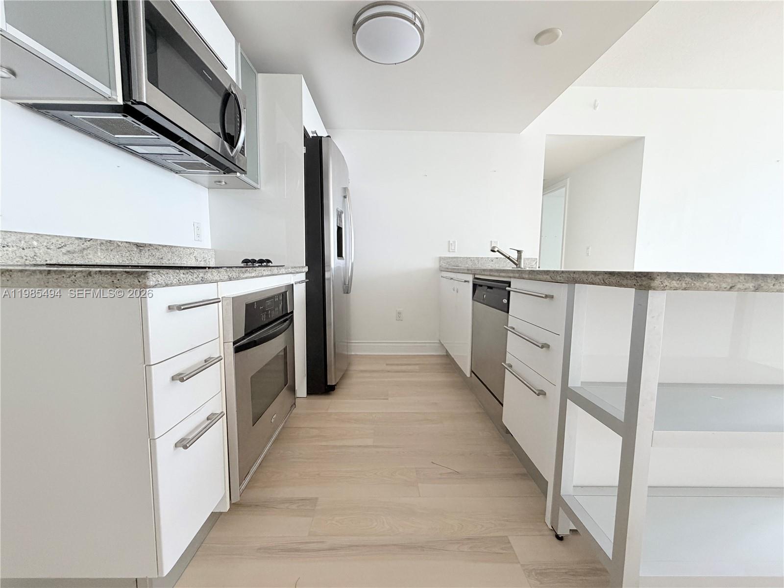 185 Southwest 7th Street, Unit 3304 Miami, FL 33130 - Photo 3 of 17 a kitchen with white cabinets and white appliances