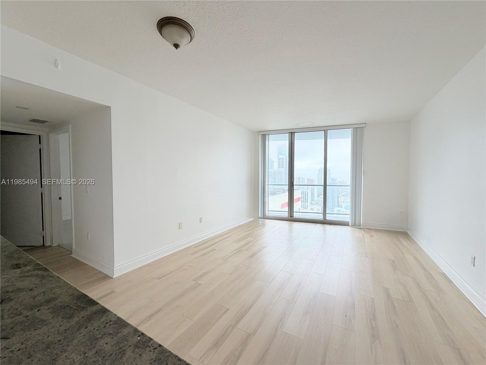 185 Southwest 7th Street, Unit 3304 Miami, FL 33130 - Photo 4 of 17 wooden floor in an empty room with a window