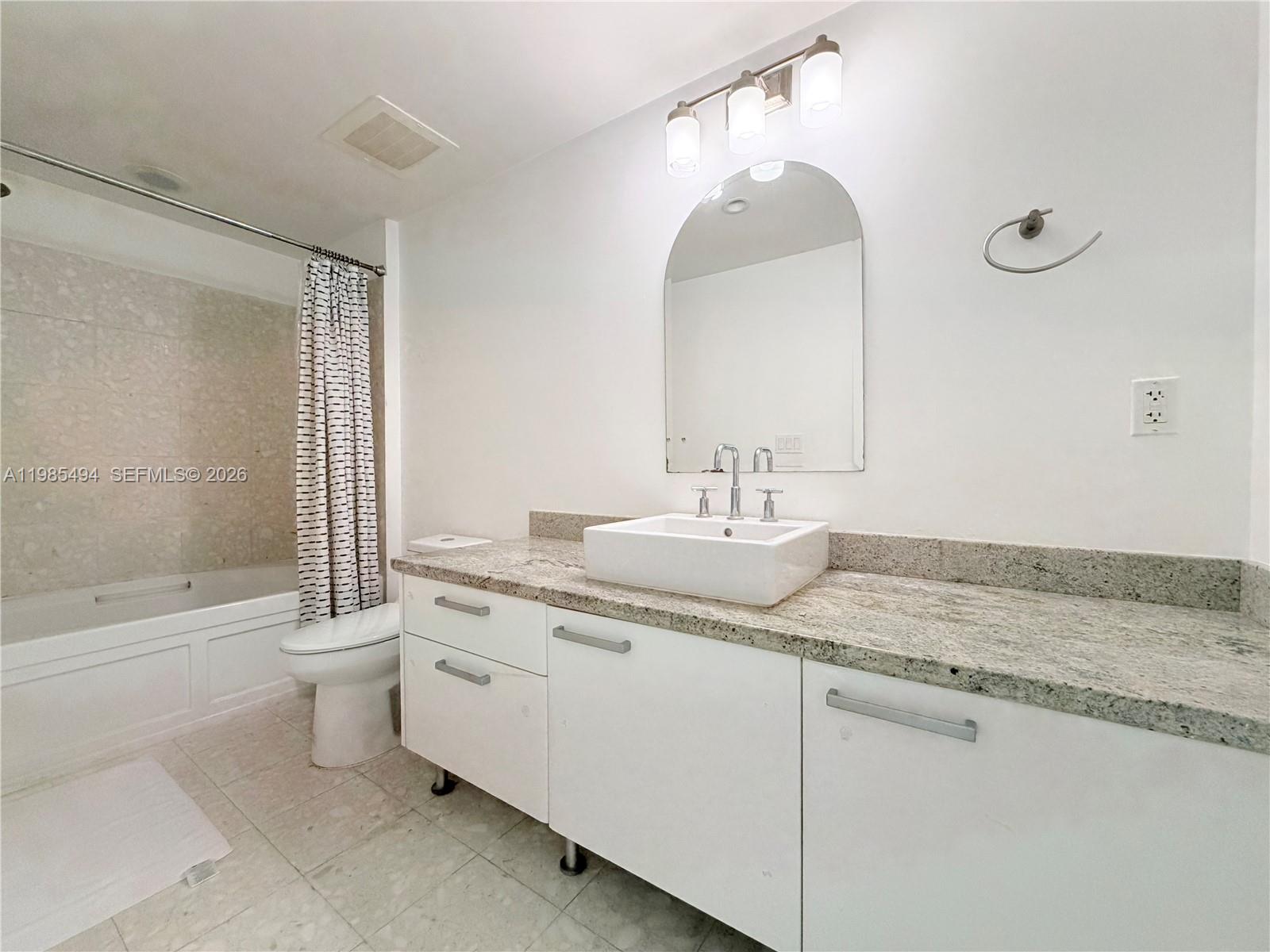 185 Southwest 7th Street, Unit 3304 Miami, FL 33130 - Photo 7 of 17 a bathroom with a granite countertop sink a toilet and a bathtub