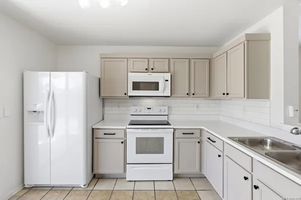 a kitchen with white cabinets and white appliances