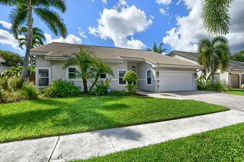 a front view of a house with a garden and palm tree